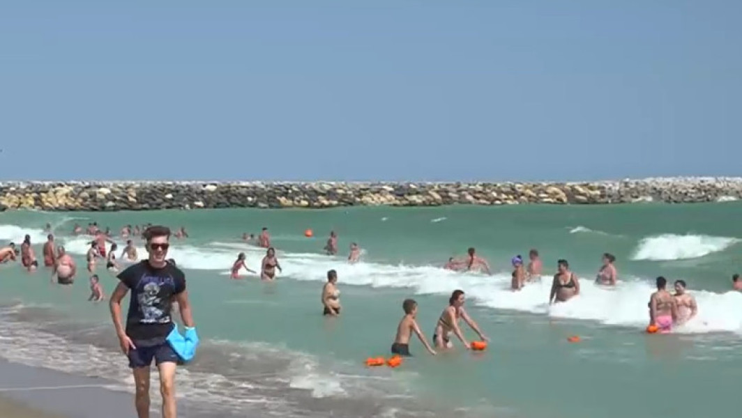 Turist scos cu forța din apă și încătușat de jandarmi, în stațiunea Venus. Pe litoral sunt valuri mari și e arborat steagul roșu